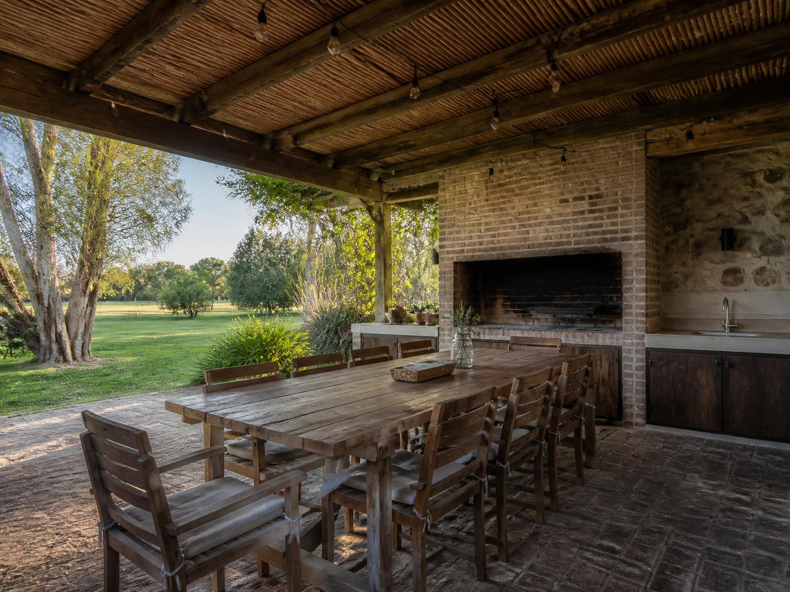 Zona de parrilla con pérgola de madera y mesa larga al aire libre