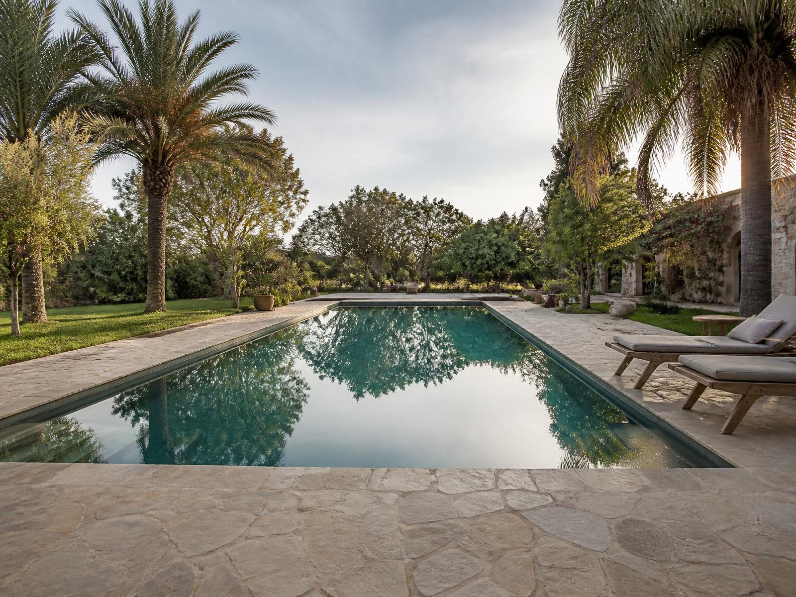Piscina integrada al jardín de una casa de campo rodeada de árboles